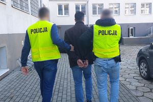 Policjanci prowadzą zatrzymanego mężczyznę
