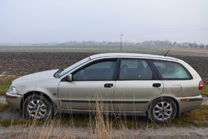 Samochód stojący na drodze gruntowej w polach.