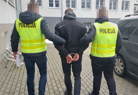 Policjanci prowadza zatrzymanego mężczyznę