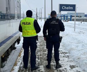 Zdjęcie przedstawiające funkcjonariusza Policji oraz Straży Ochrony Kolei, którzy wspólnie patrolują tereny kolejowe