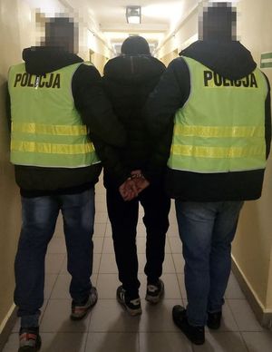 zdjęcie przedstawiające dwóch funkcjonariuszy Policji, którzy prowadzą zatrzymaną osobę