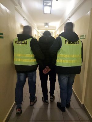 zdjęcie przedstawiające dwóch funkcjonariuszy  Policji, którzy prowadzą osobę zatrzymaną