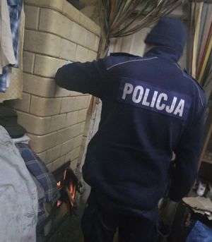 Policjant dokłada opał do pieca.