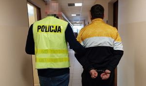 Policjant prowadzi zatrzymanego mężczyznę