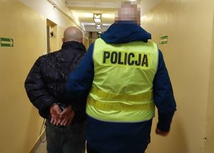 Policjant prowadzi zatrzymanego mężczyznę