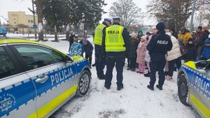 Policjanci ruchu drogowego prowadzą przy radiowozach pogadankę z dziećmi