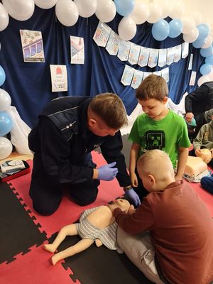 Policjant pokazuje dzieciom jak udzielać pierwszej pomocy
