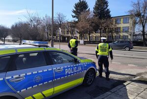 Policjanci przy radiowozie obserwują ruch na drodze