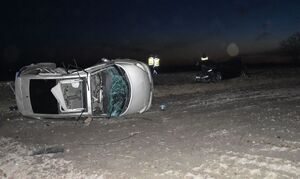 Zdjęcie przedstawiające dwa pojazdy biorące udział w zdarzeniu drogowym. W tle widoczni policjanci w kamizelkach odblaskowych.