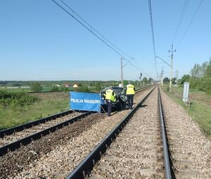 Zdjęcie przedstawiające policjantów w żółtych kamizelkach podczas czynności do wypadku na torach kolejowych