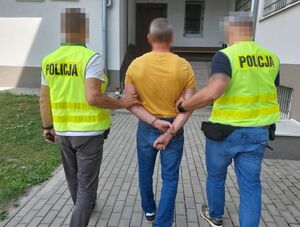Policjanci prowadzą zatrzymanego mężczyznę.