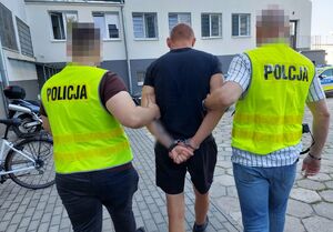 Policjanci prowadzą zatrzymanego mężczyznę.