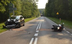 Samochód z rozbitym przodem i leżący na jezdni motocykl.
