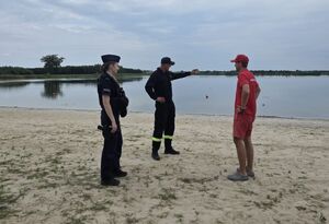 Policjantka, strażak i dwoje i ratownik wodny na plaży nad wodą.