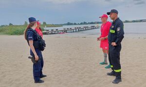 Policjantka, strażak i dwoje ratowników wodnych na plaży nad wodą.
