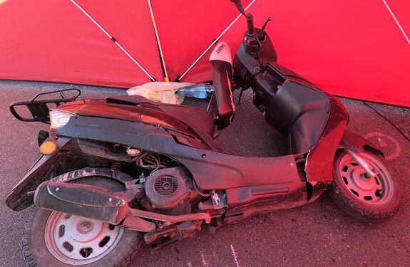 Leżący na jezdni motorower.