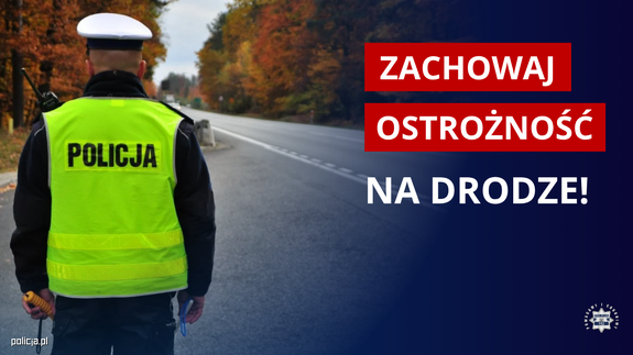 Policjant obserwuje drogę i napis zachowaj ostrożność na drodze.
