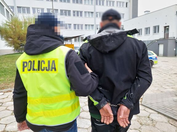 Policjant prowadzi zatrzymanego.