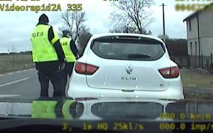 Klatka stop z videorejestratora z dwoma policjantami kontrolującymi samochód