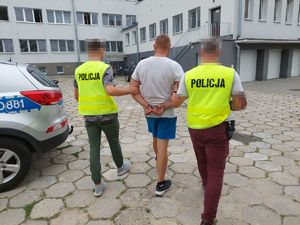 policjanci prowadzą zatrzymaną osobę